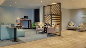 A modern hotel lobby with a reception desk, seating area, and a large water dispenser. - Holiday Inn Mansfield - Alfreton by IHG (Alfreton)