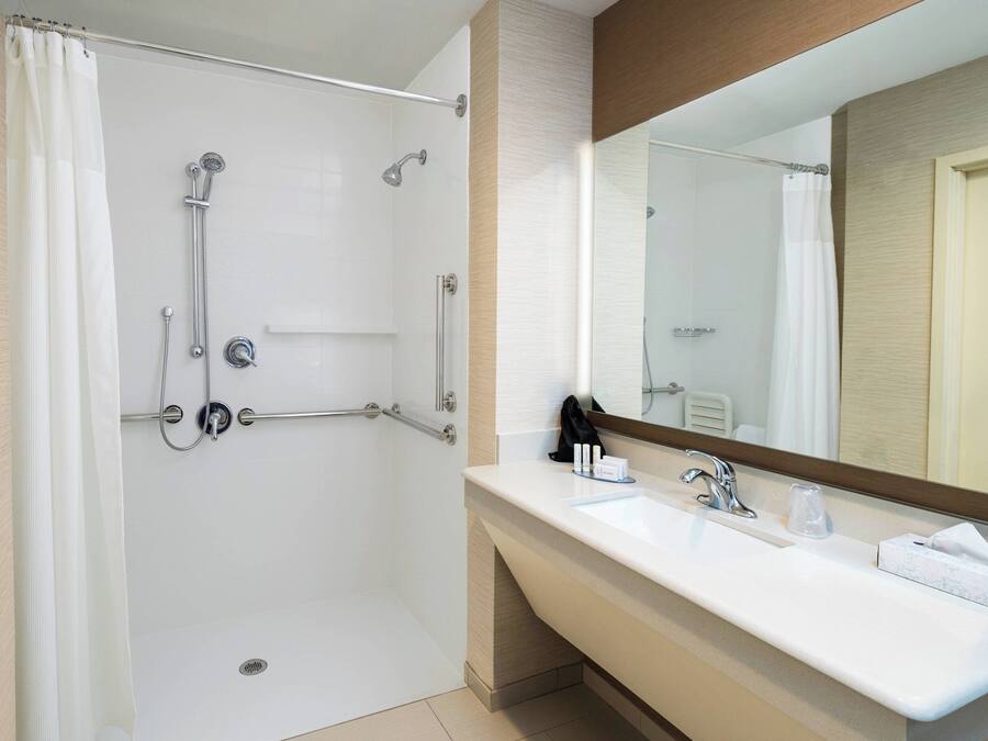 A modern bathroom with a walk-in shower, a sink with a mirror, and a towel rack.