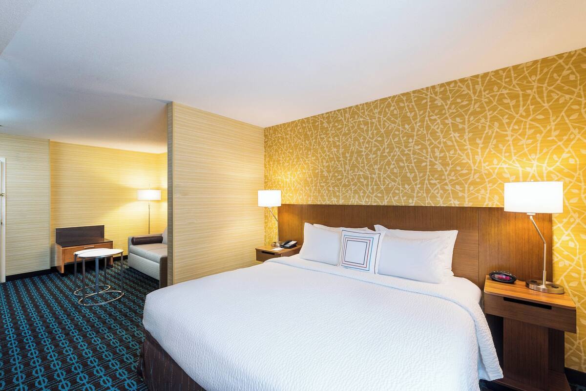 A hotel room with a large bed, two bedside tables with lamps, a small desk, and a chair.