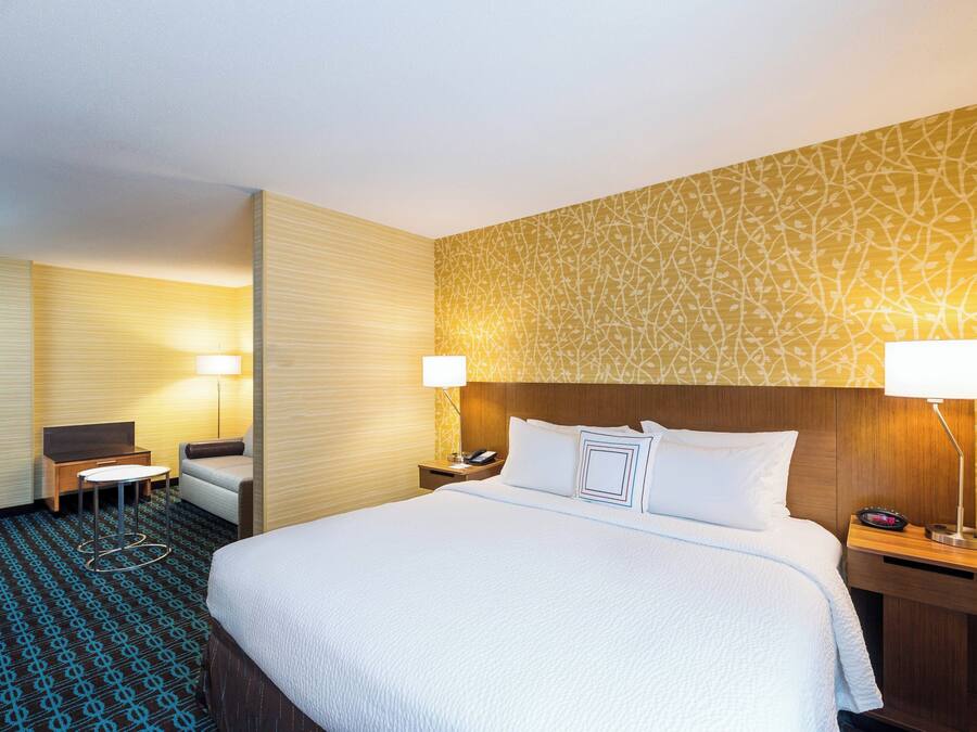A hotel room with a large bed, two bedside tables with lamps, a small desk, and a chair.
