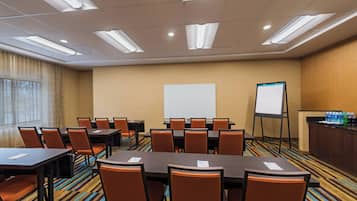 A conference room with tables and chairs, a whiteboard, and a projection screen.