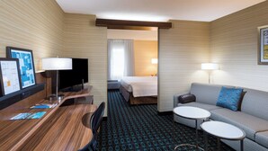 Habitación de hotel con cama, sofá, escritorio con silla, televisor y una mesita.