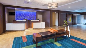 Un área de recepción moderna con un mostrador de madera, una pared decorativa azul grande y una alfombra colorida.