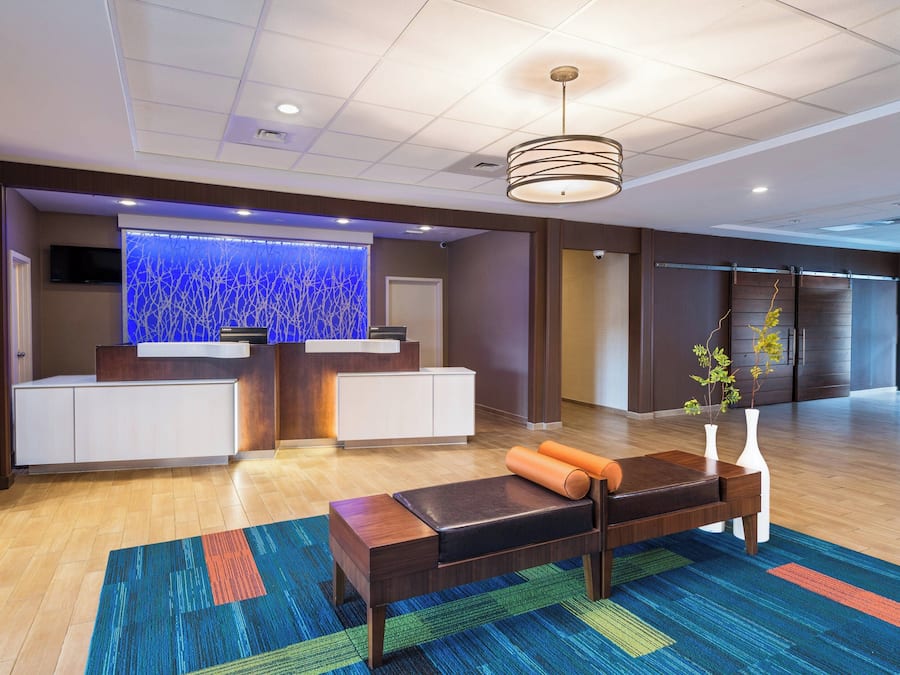 Uma área de recepção moderna com um balcão de madeira, uma parede decorativa azul e um tapete colorido.