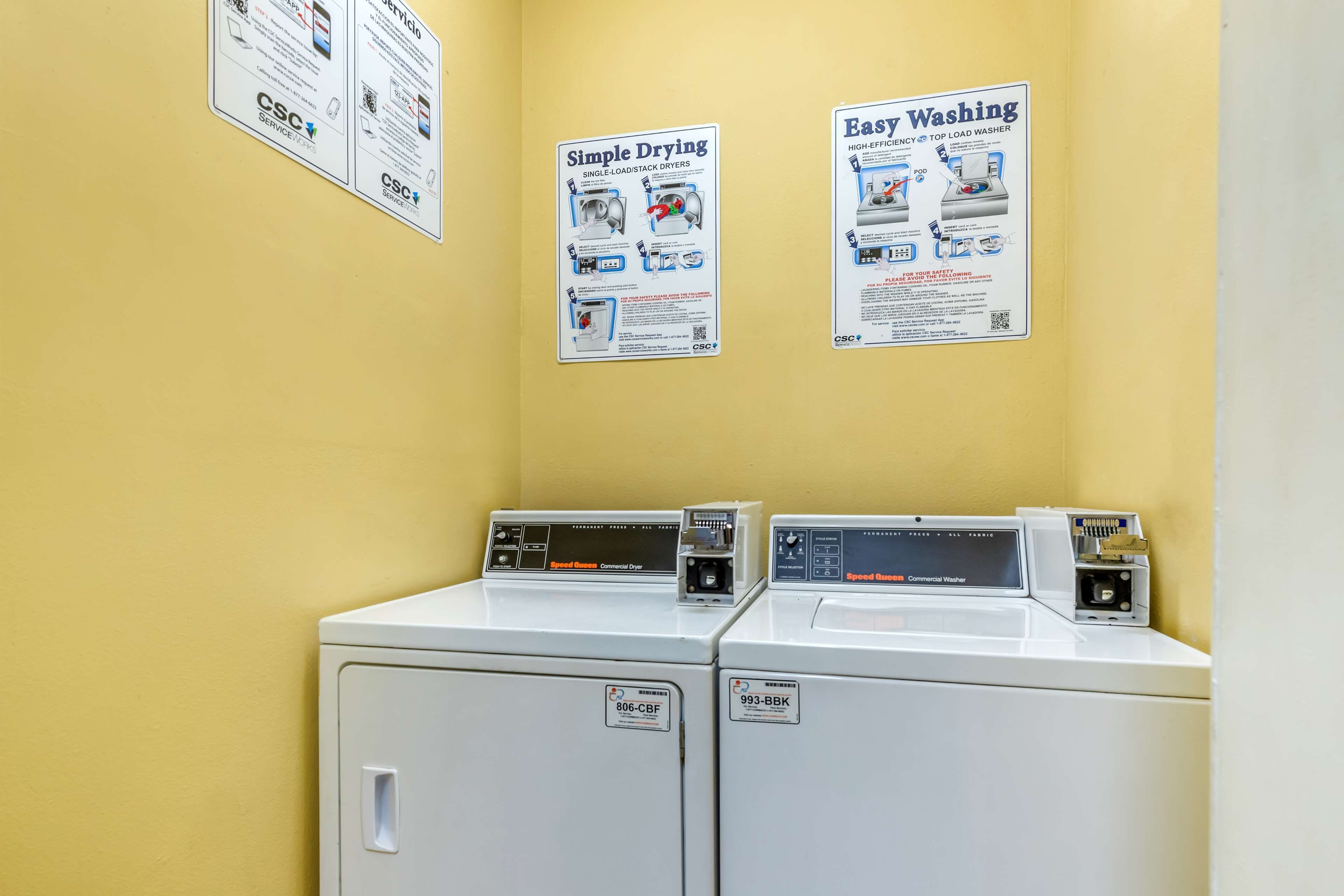 A laundry area with two washing machines and two instructional posters on the wall.