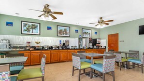 A restaurant with wooden cabinets, a counter, and multiple tables and chairs.