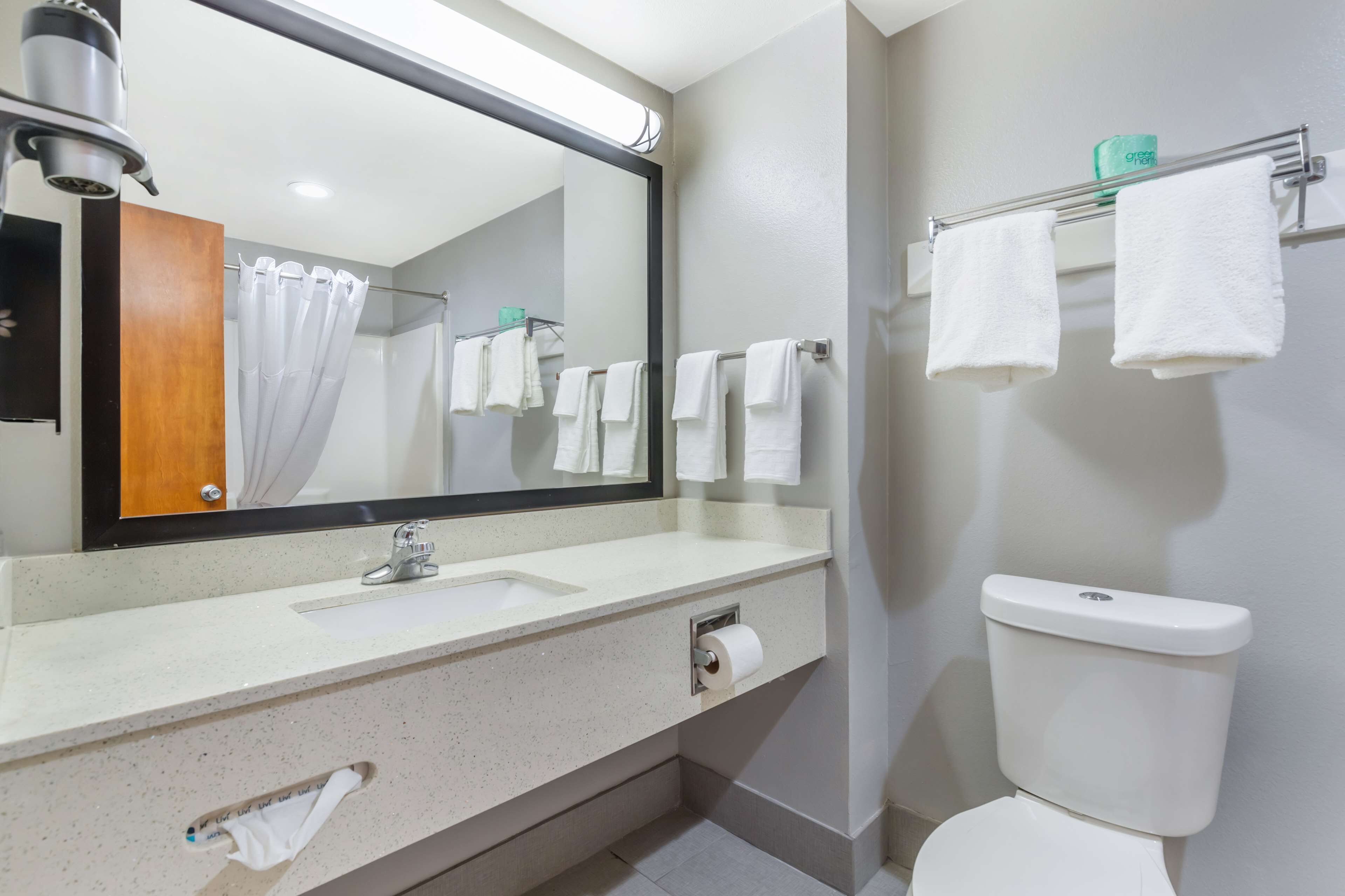 Een badkamer met een wastafel, spiegel, toilet en handdoekhouder.