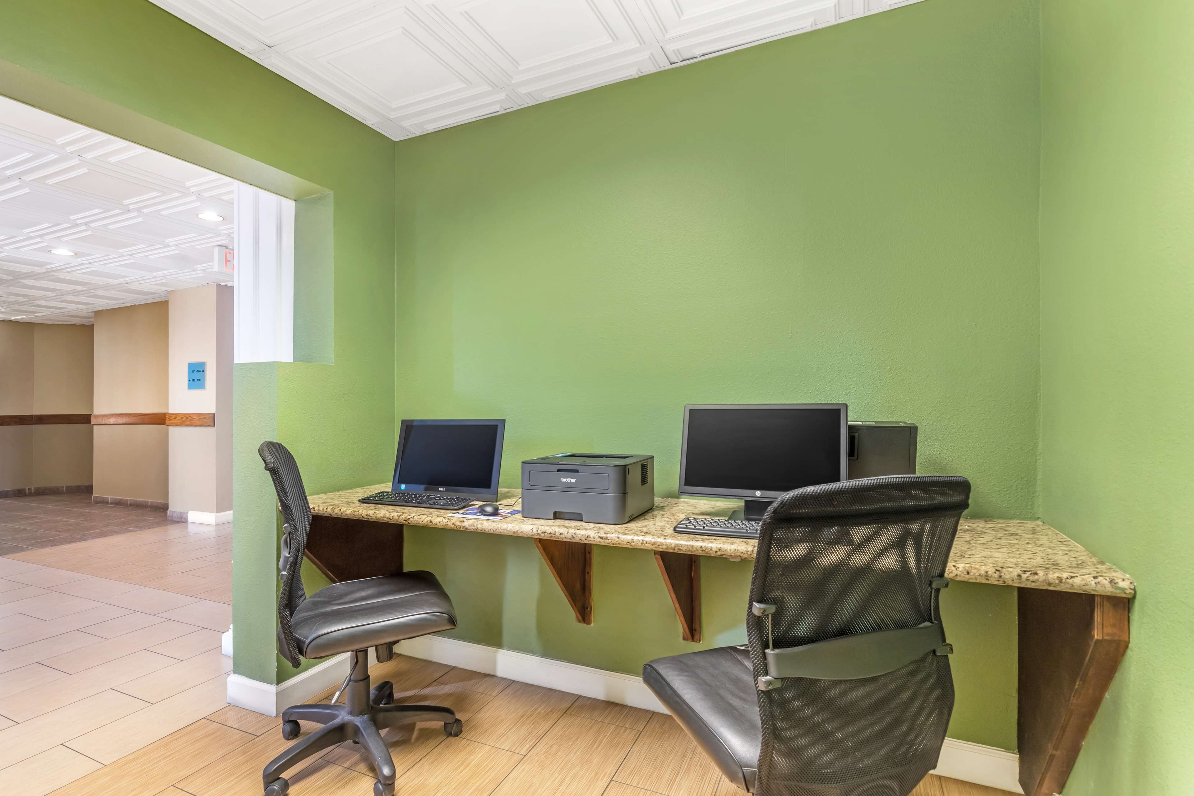 Een werkplek met twee computers, een printer en twee stoelen.