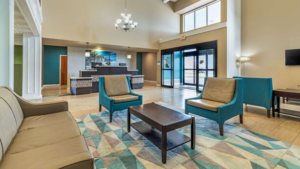 A spacious lobby with teal armchairs, a coffee table, and a patterned rug. A reception desk is visible in the background. - Best Western Port Lavaca Inn (Port Lavaca)