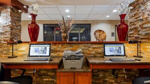 Una mesa de recepción con dos computadoras de escritorio HP, una impresora Brother y jarrones decorativos.