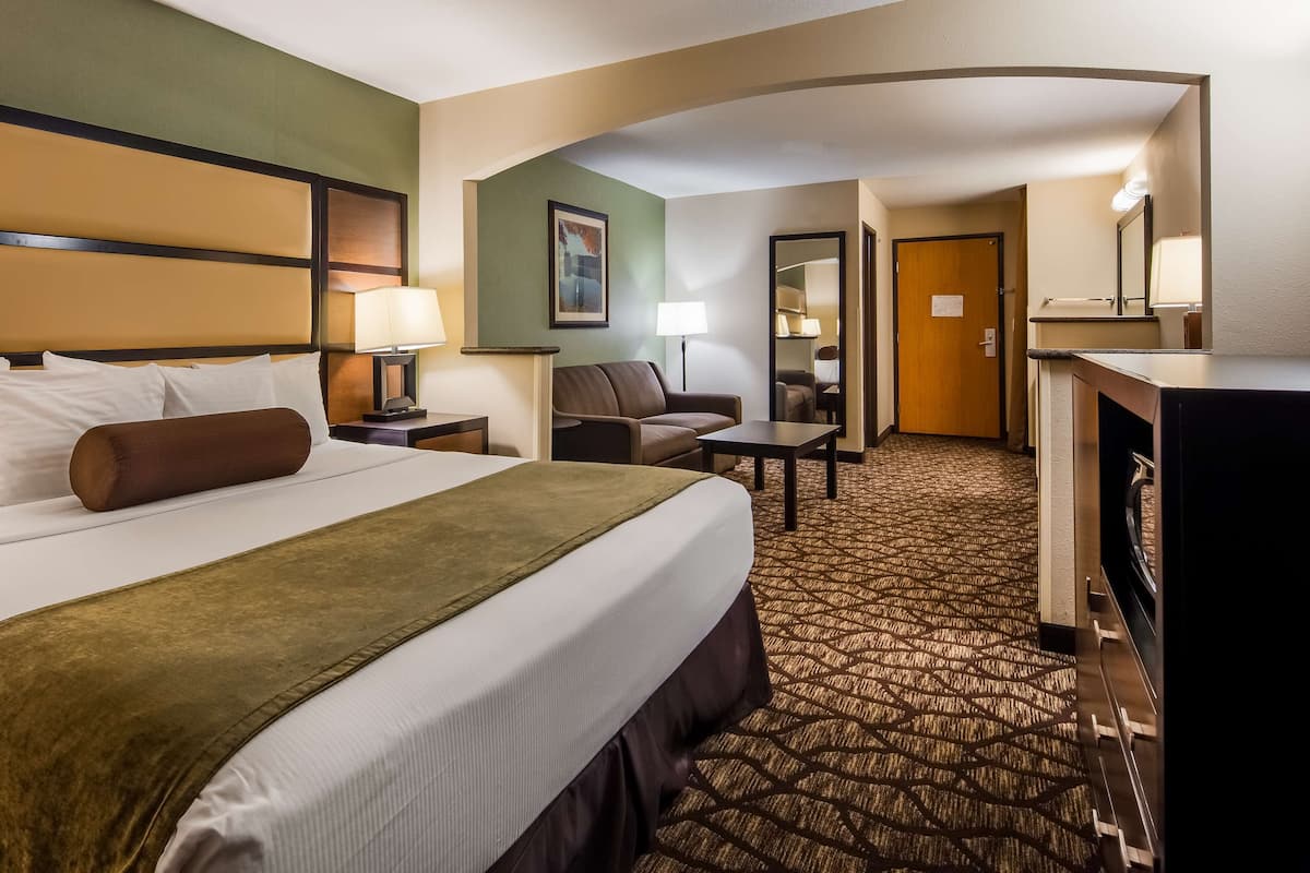Una habitación de hotel con una cama grande, un escritorio, una silla y un microondas.