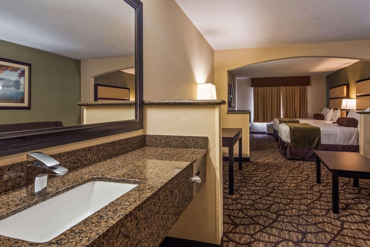 Une chambre d’hôtel avec un lavabo en granit, un lit, un canapé et une petite table.