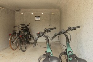 Uma área de estacionamento para bicicletas, com duas bicicletas e uma bicicleta elétrica verde.