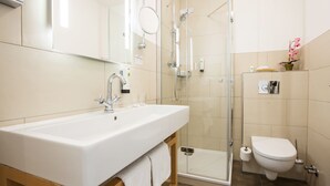 Un baño moderno con un lavamanos grande, una ducha con mampara de vidrio y un inodoro.