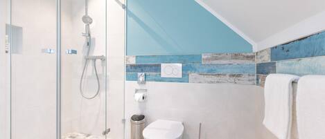 Un baño moderno con cabina de ducha de vidrio, inodoro y lavabo.