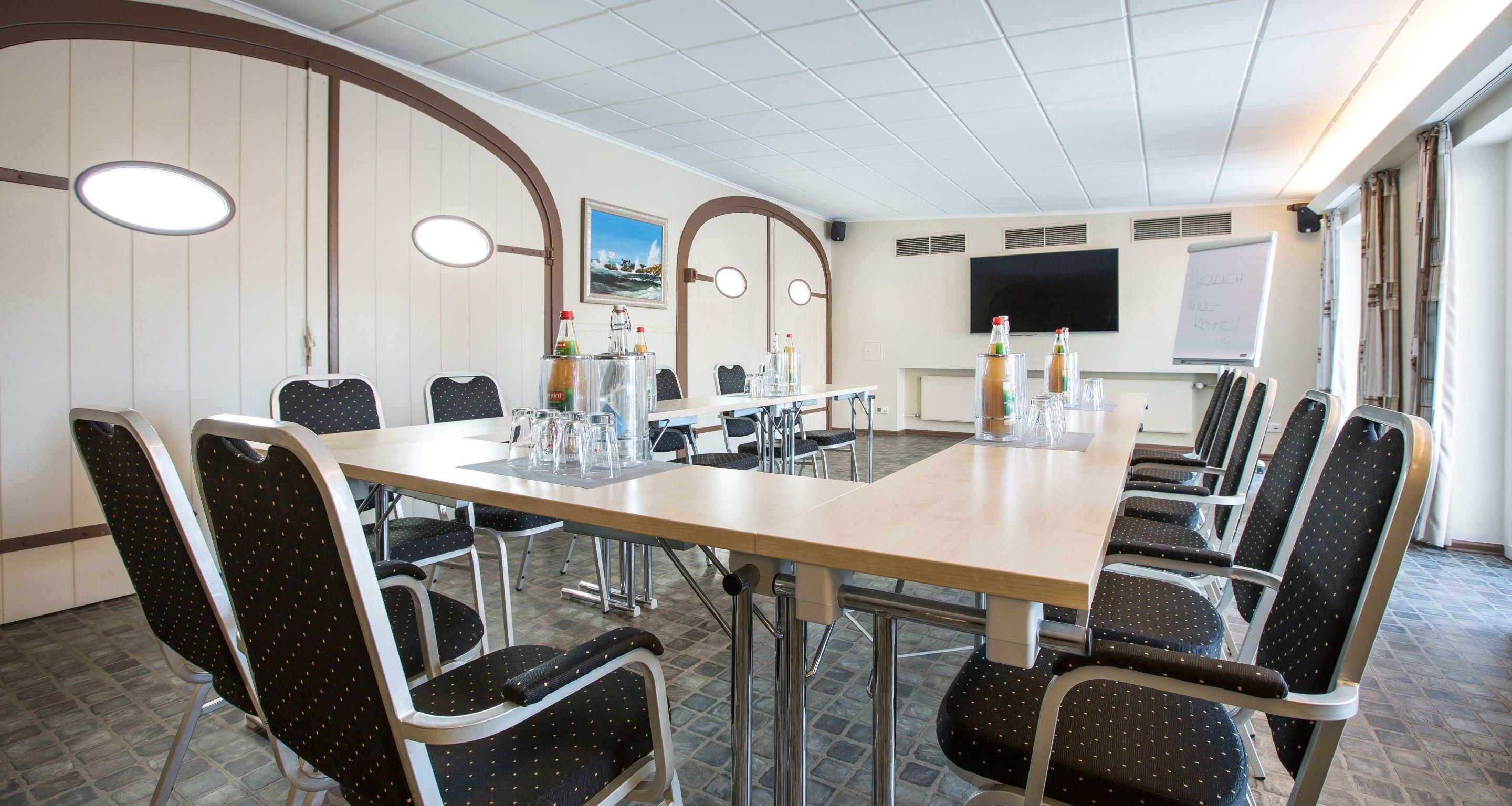 A conference room with a long table, chairs, and a whiteboard.