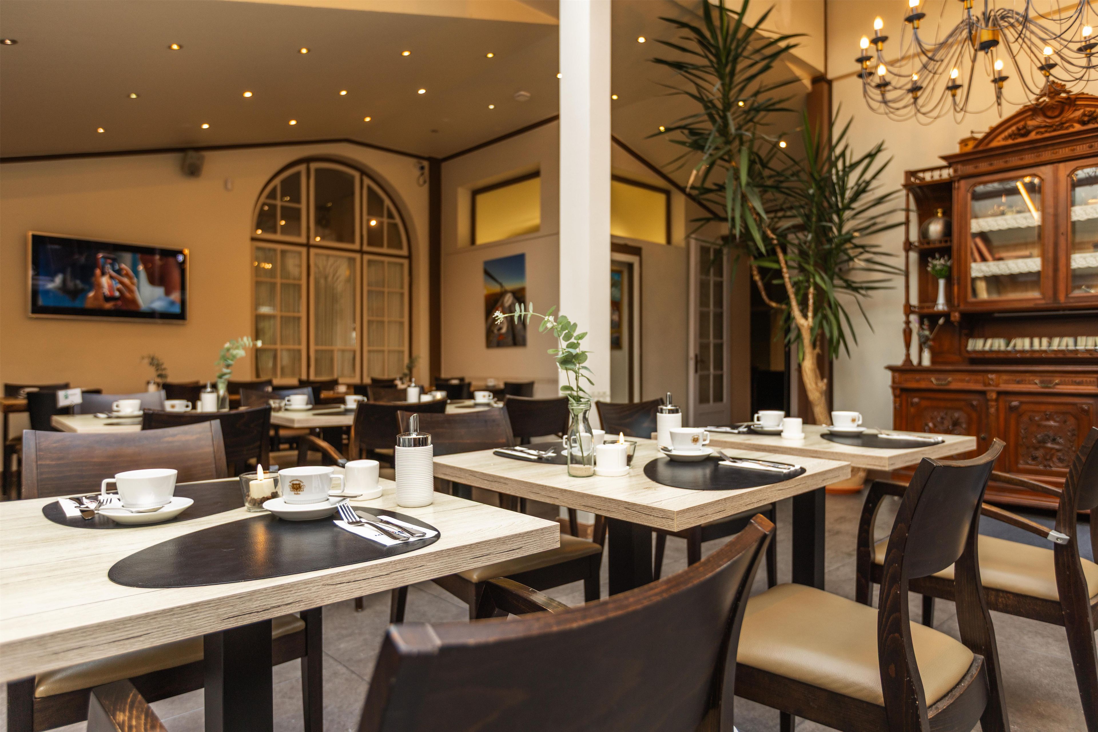 Un restaurante con varias mesas, sillas y una planta grande.