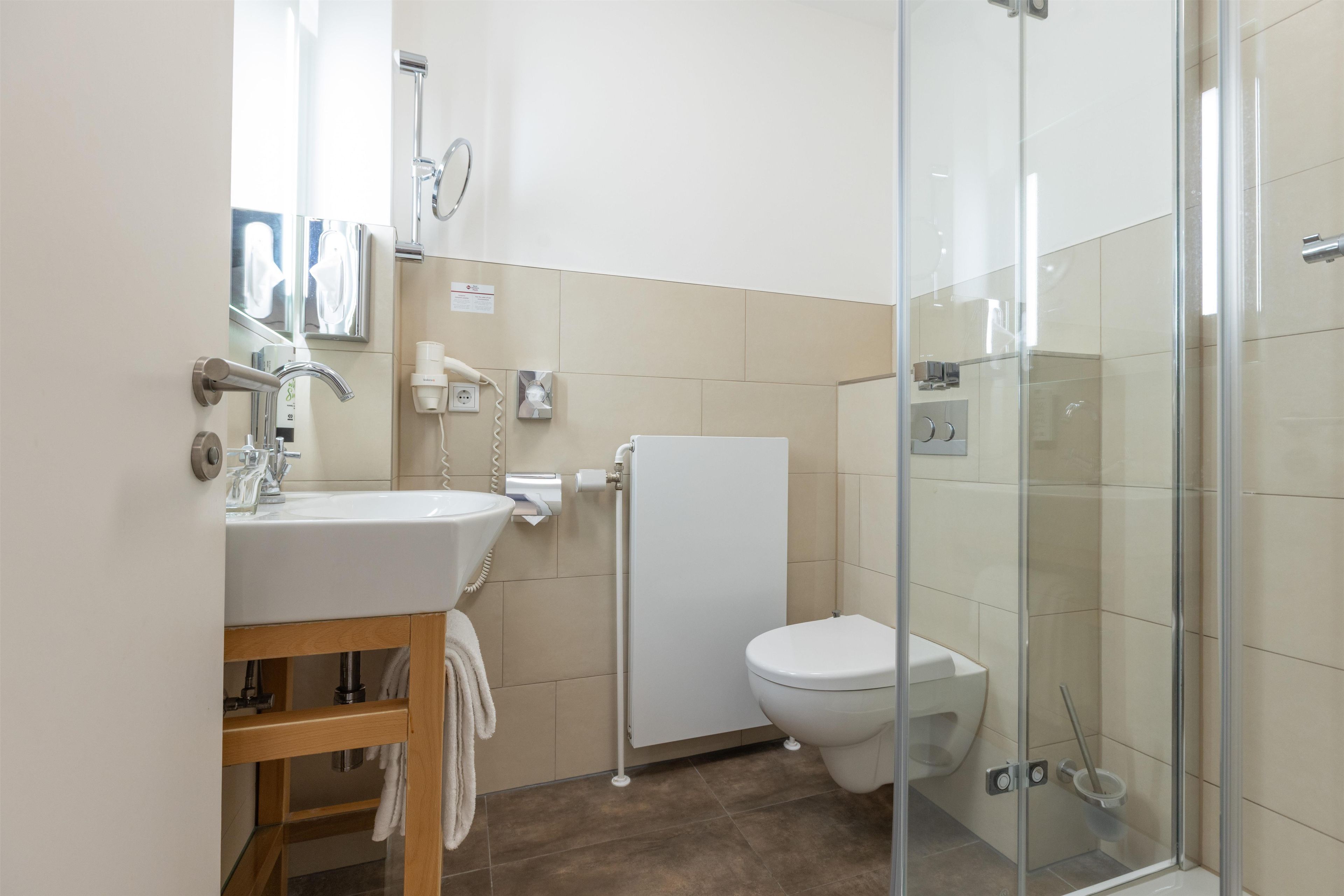 A modern bathroom with a glass shower enclosure, a white toilet, and a sink with a mirror above it.