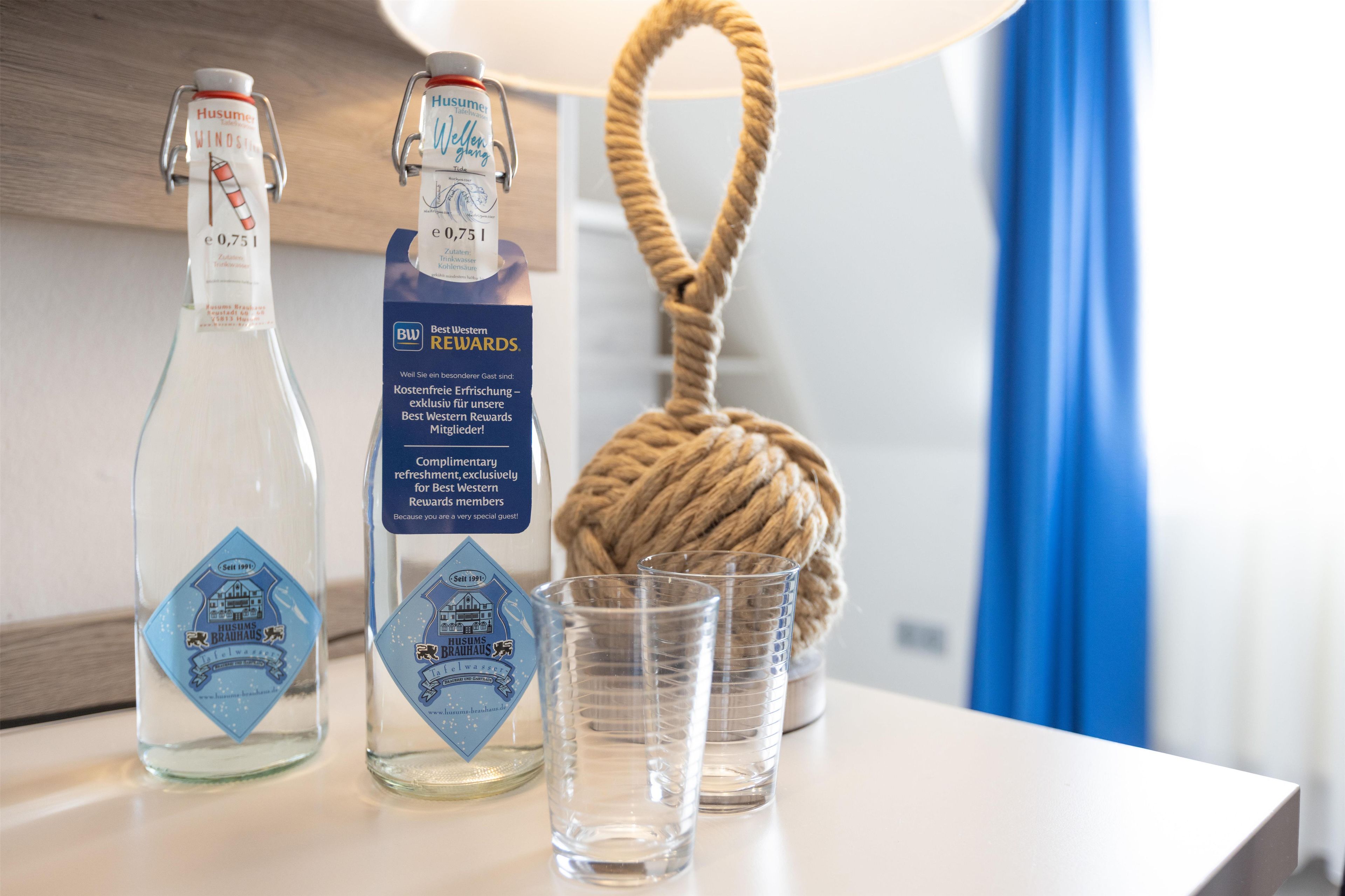 Twee waterflessen, een Best Western Rewards kaart en twee glaasjes op een tafel.