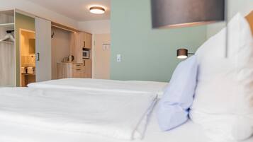 Habitación de hotel con cama, armario, microondas y lámpara.
