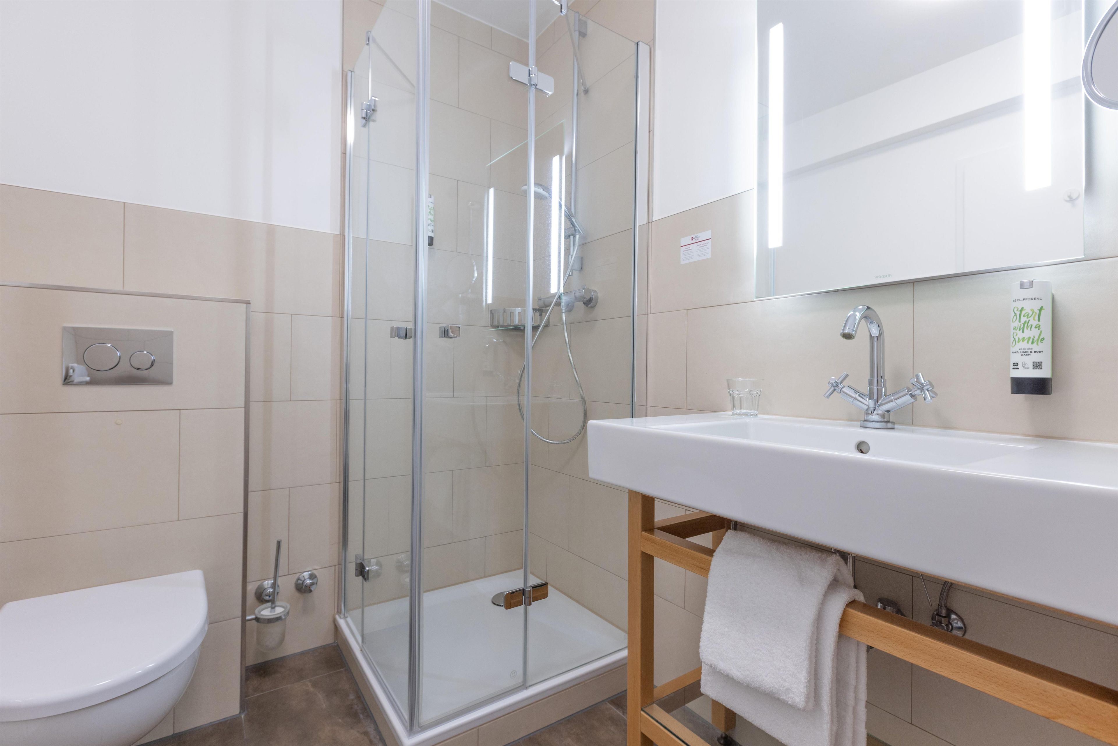 A modern bathroom with a glass-enclosed shower, a white sink, and a toilet.