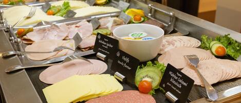 Un bufé con diversas opciones de comida, incluyendo embutidos, quesos y frutas.