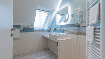 Un baño moderno con tragaluz, un espejo grande, un lavabo y un perchero para toallas.