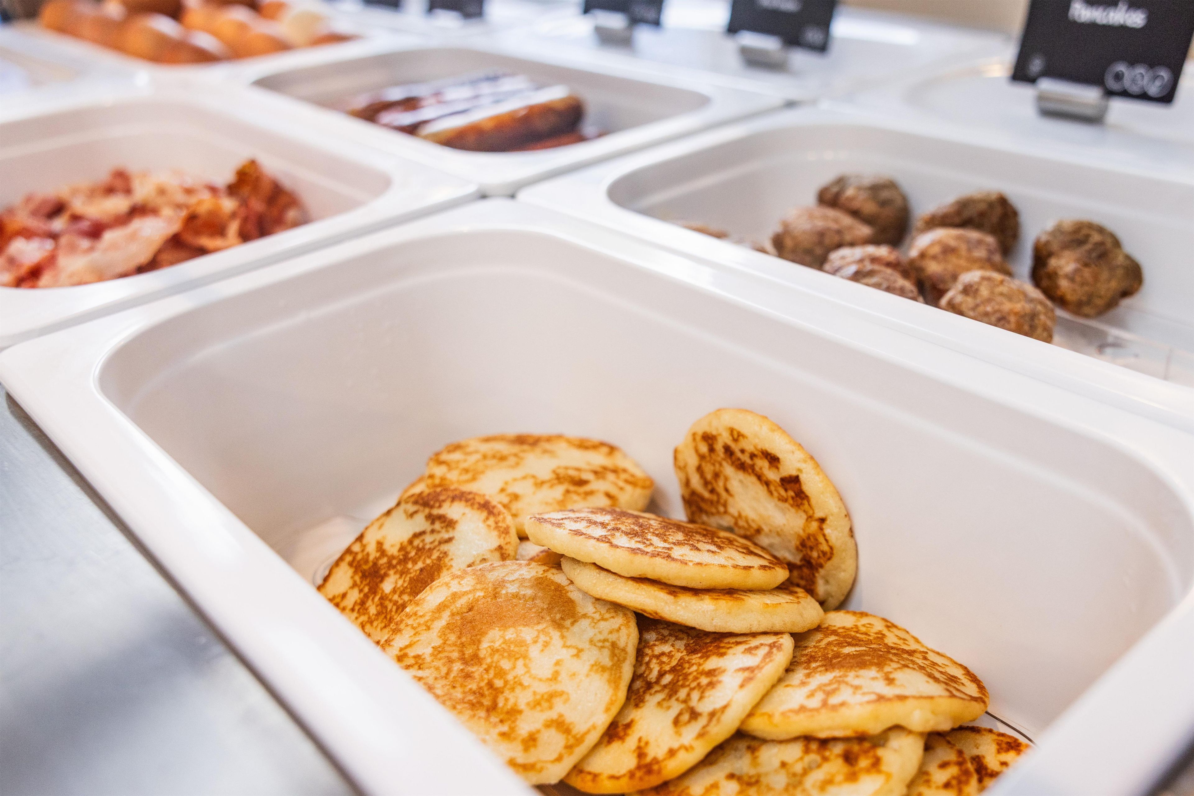 Un buffet proposant une variété de plats, notamment des crêpes, des boulettes de viande et d’autres mets.