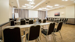 Un salón de conferencias con varias mesas y sillas, una pizarra y un cuadro en la pared.