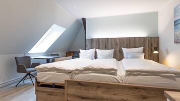 Een moderne slaapkamer met een schuine kap, een houten bed en een bureau met stoel.
