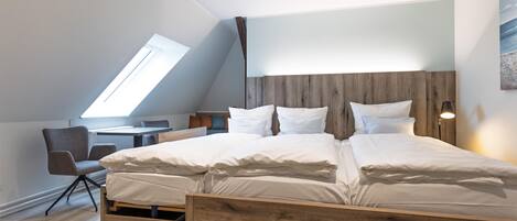 Une chambre moderne avec un plafond en pente, un lit en bois et un bureau avec une chaise.