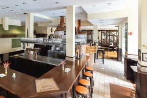 Zona de bar con taburetes, barra y un gran alambique de cobre.