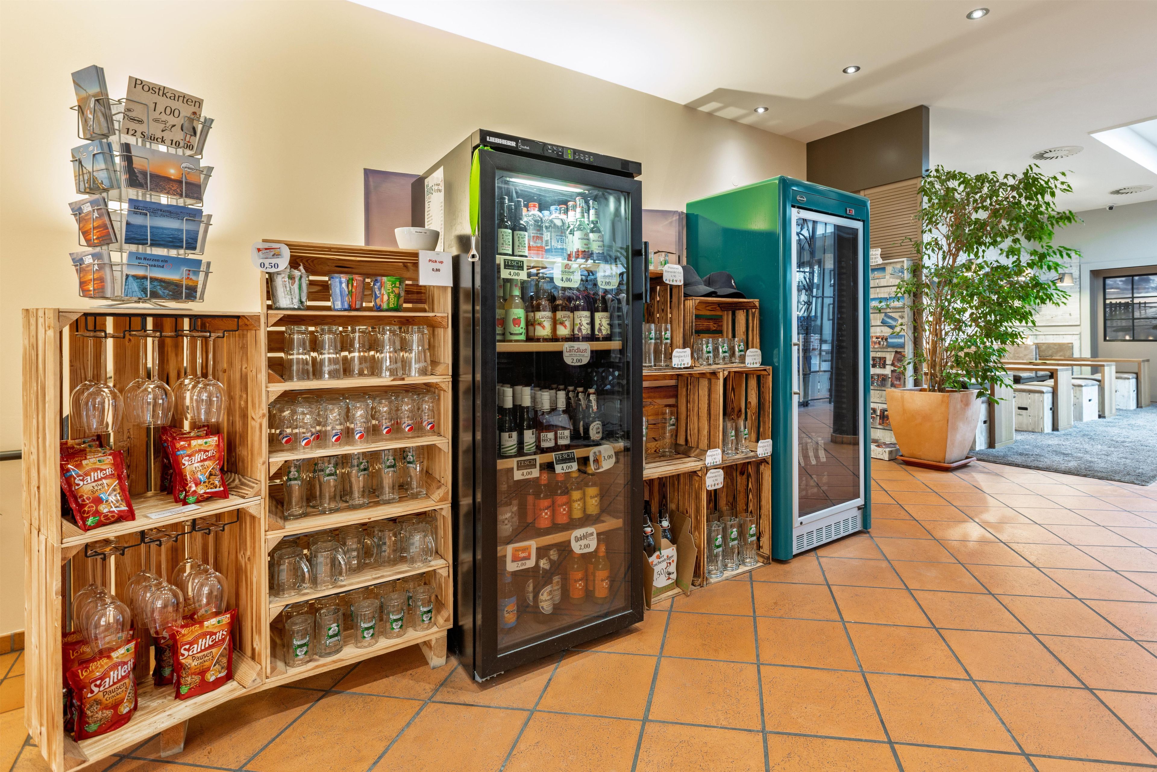 A hotel lobby with a self-service beverage station, snack dispensers, and a large potted plant.