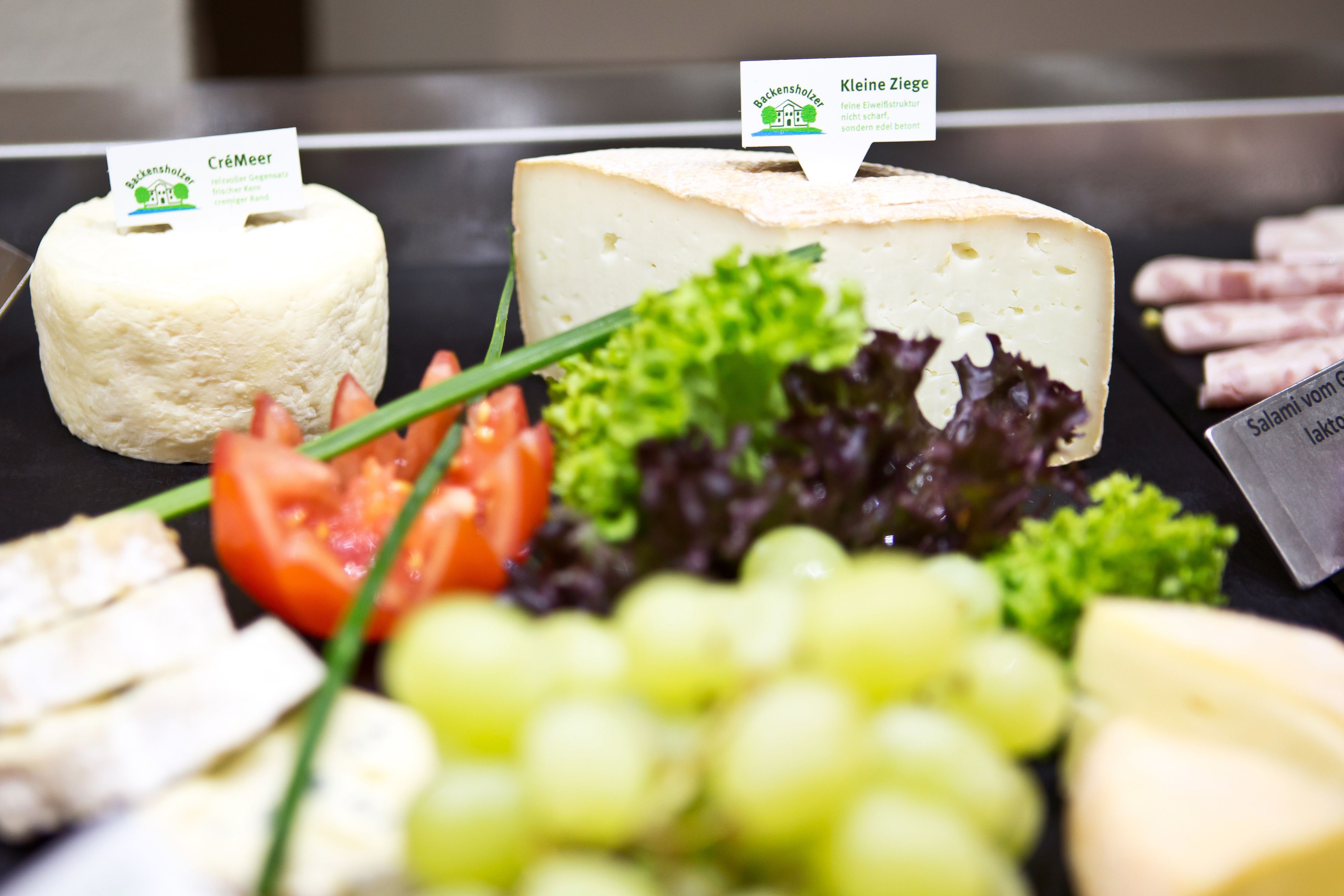 A cheese board with various cheeses, grapes, and vegetables.