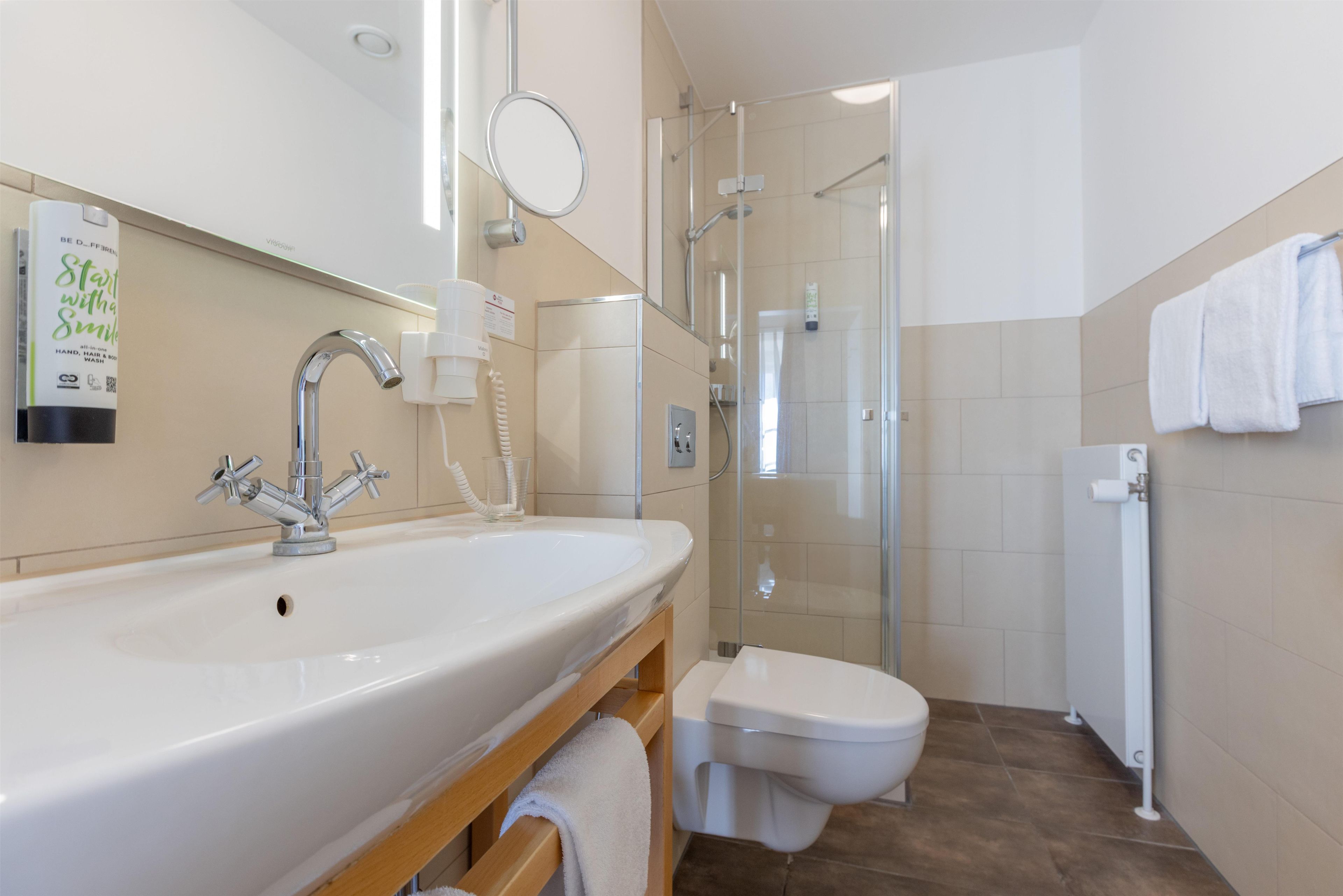 Ein modernes Badezimmer mit einem großen Waschbecken, einer Toilette und einer Duschkabine.