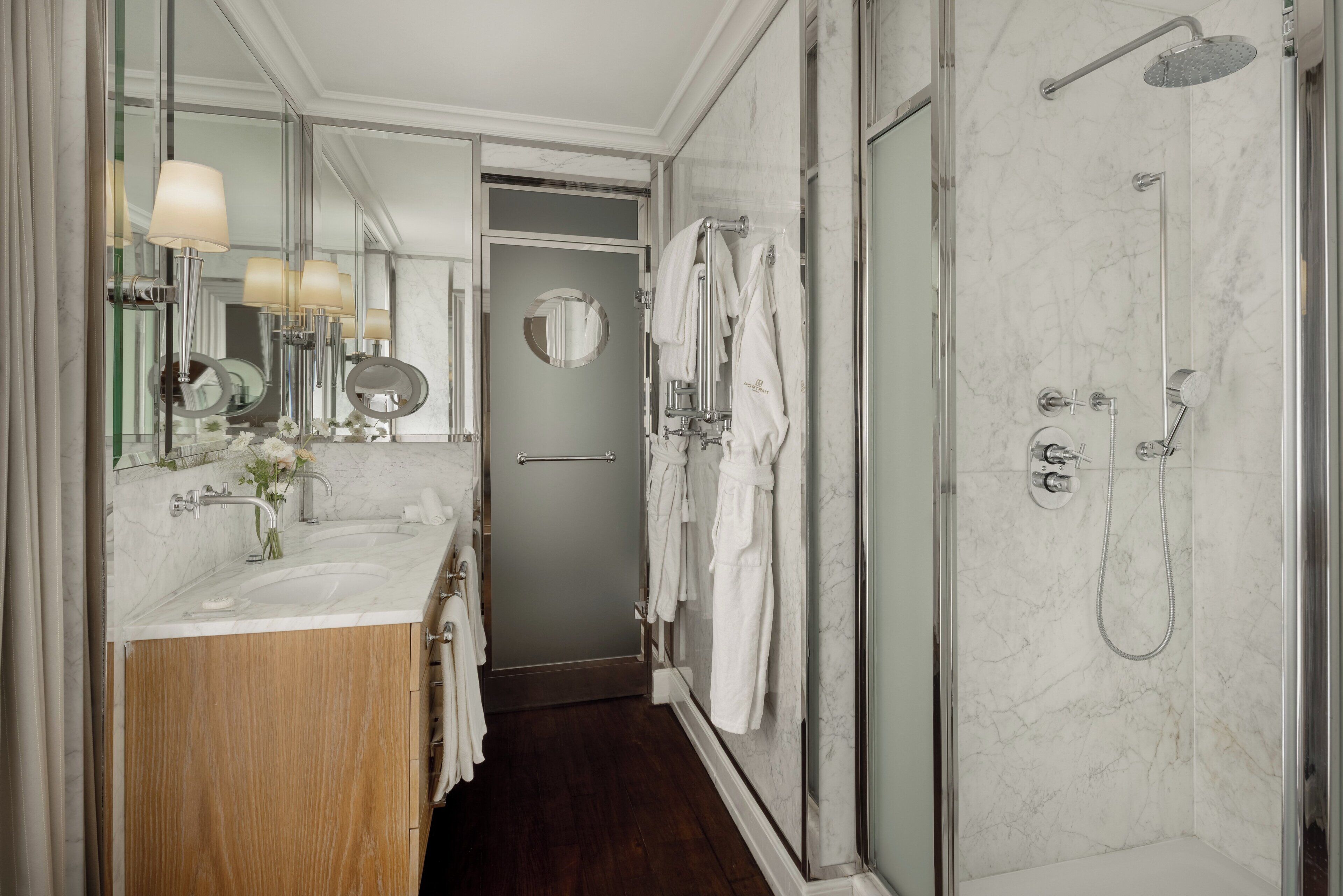 A modern bathroom with a marble sink, a glass-enclosed shower, and a wooden vanity.