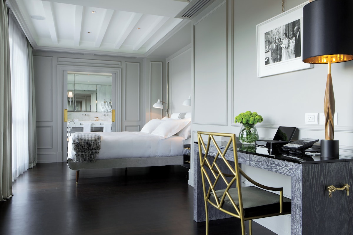 A modern hotel room with a bed, desk, and chair.