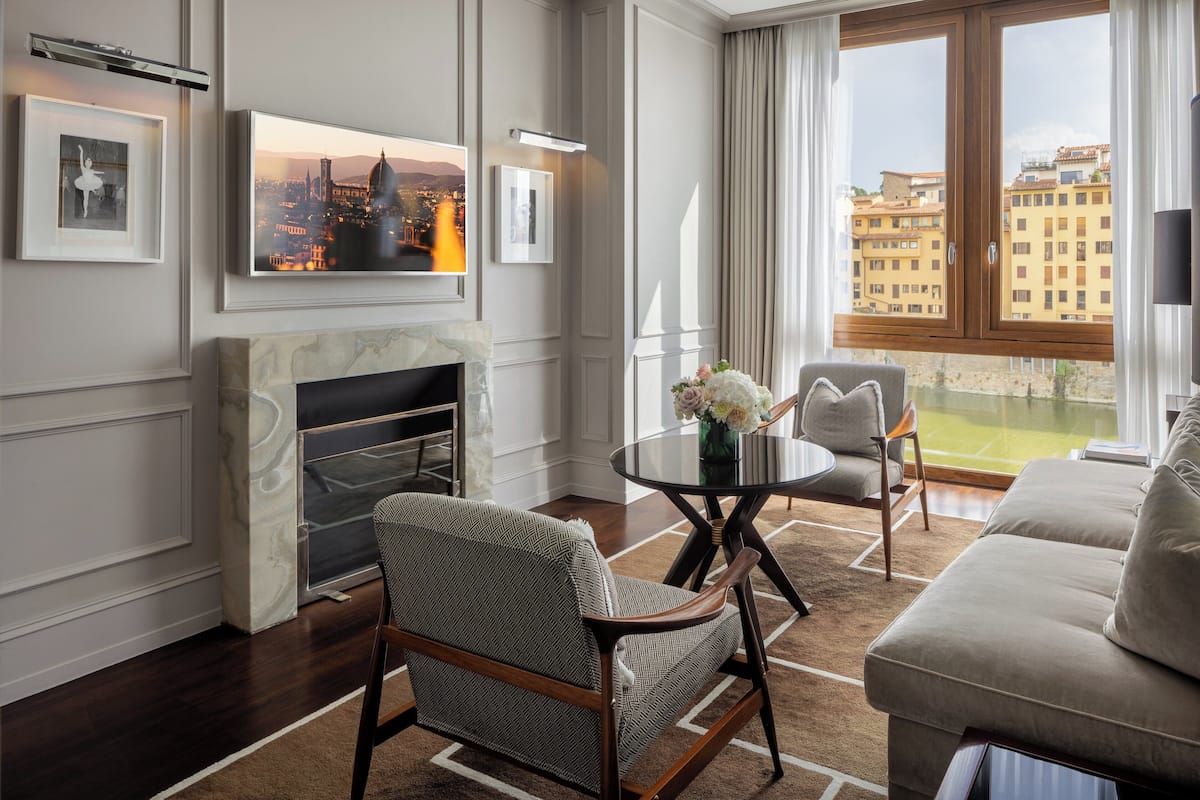 Una sala de estar moderna con chimenea, un sofá, una mesa de comedor con sillas y un ventanal con vistas a la ciudad.