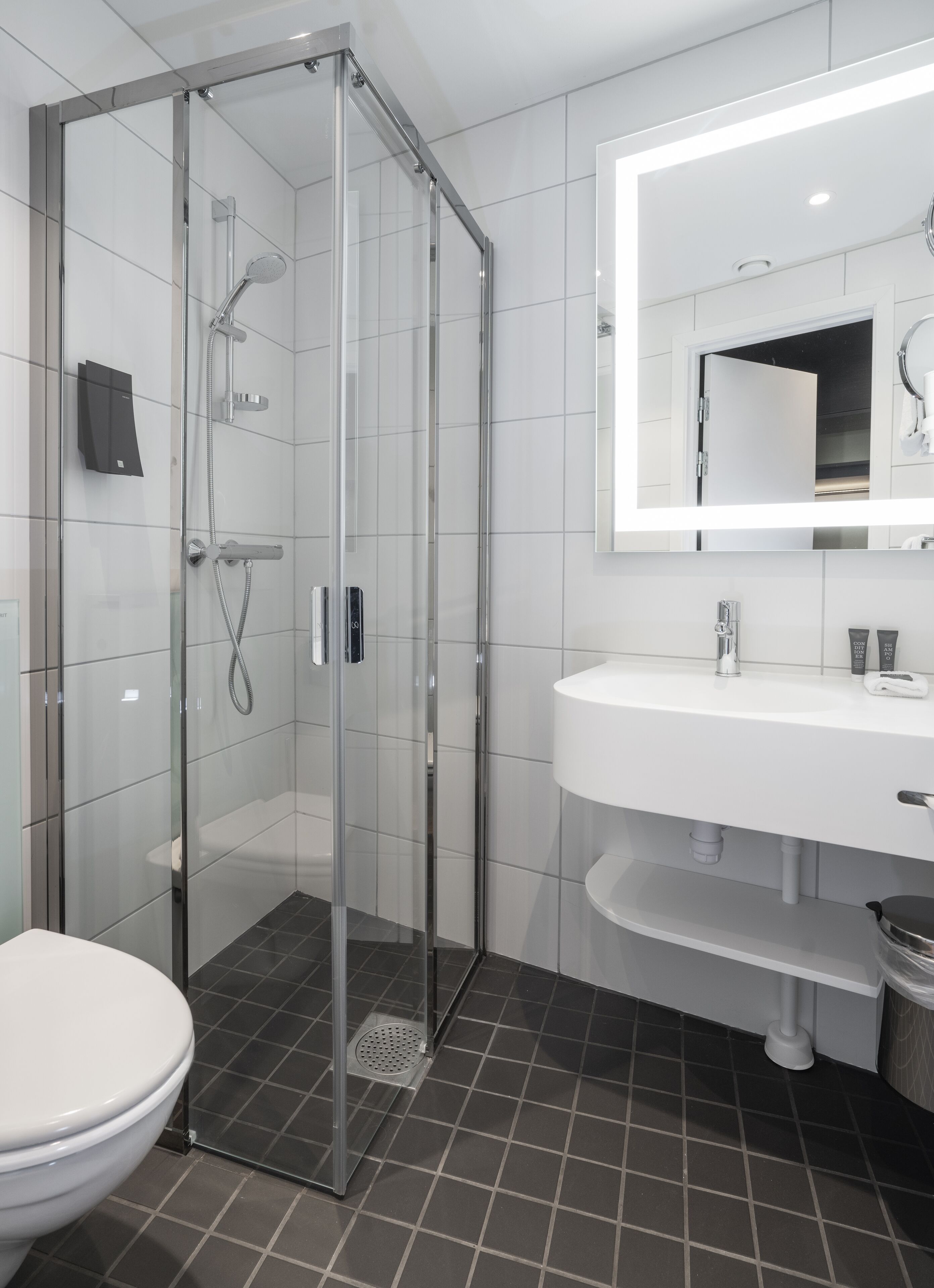 Un baño moderno con cabina de ducha de vidrio, un lavamanos blanco y un espejo grande.