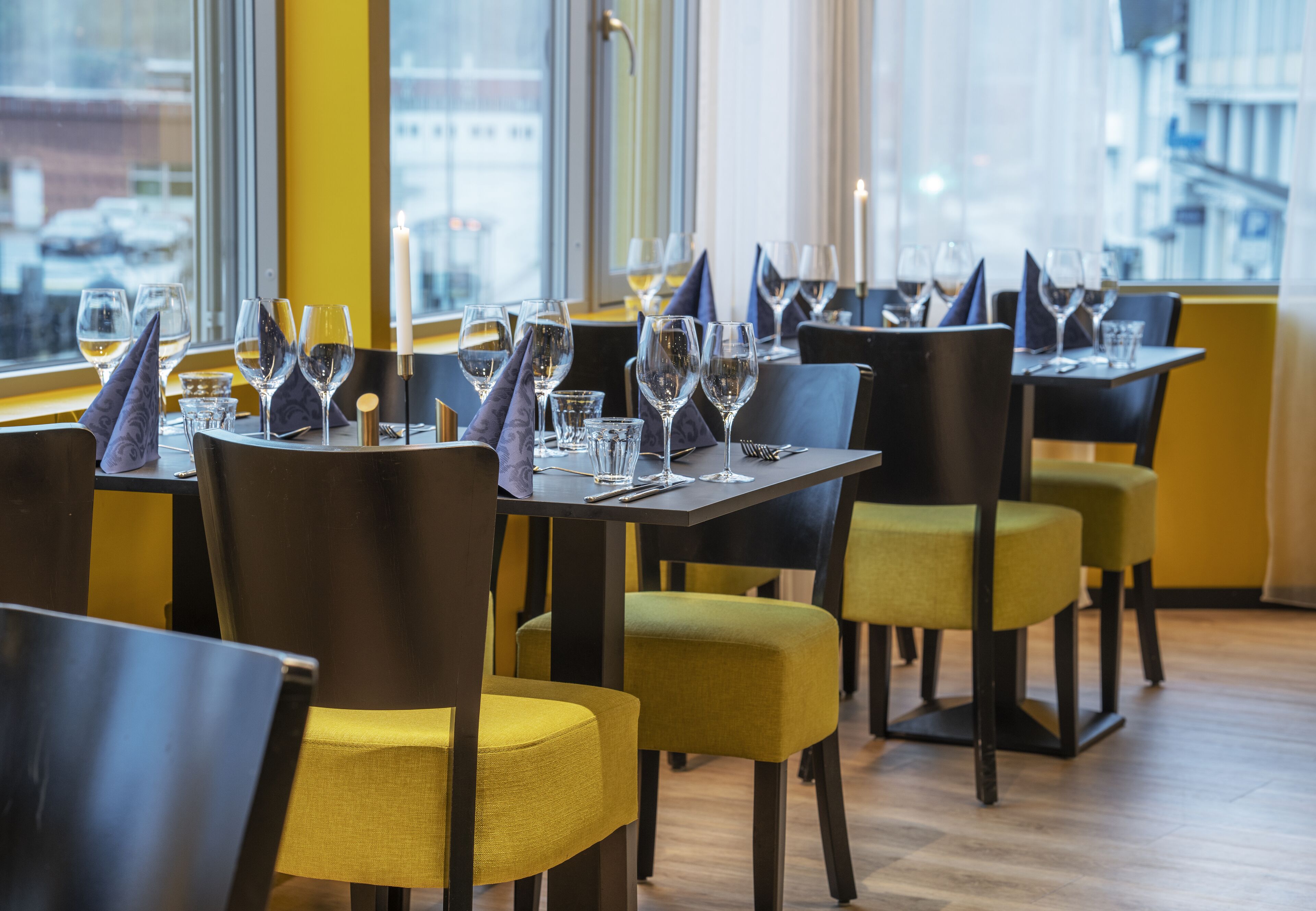 A restaurant with tables set for dining, chairs, and candles.