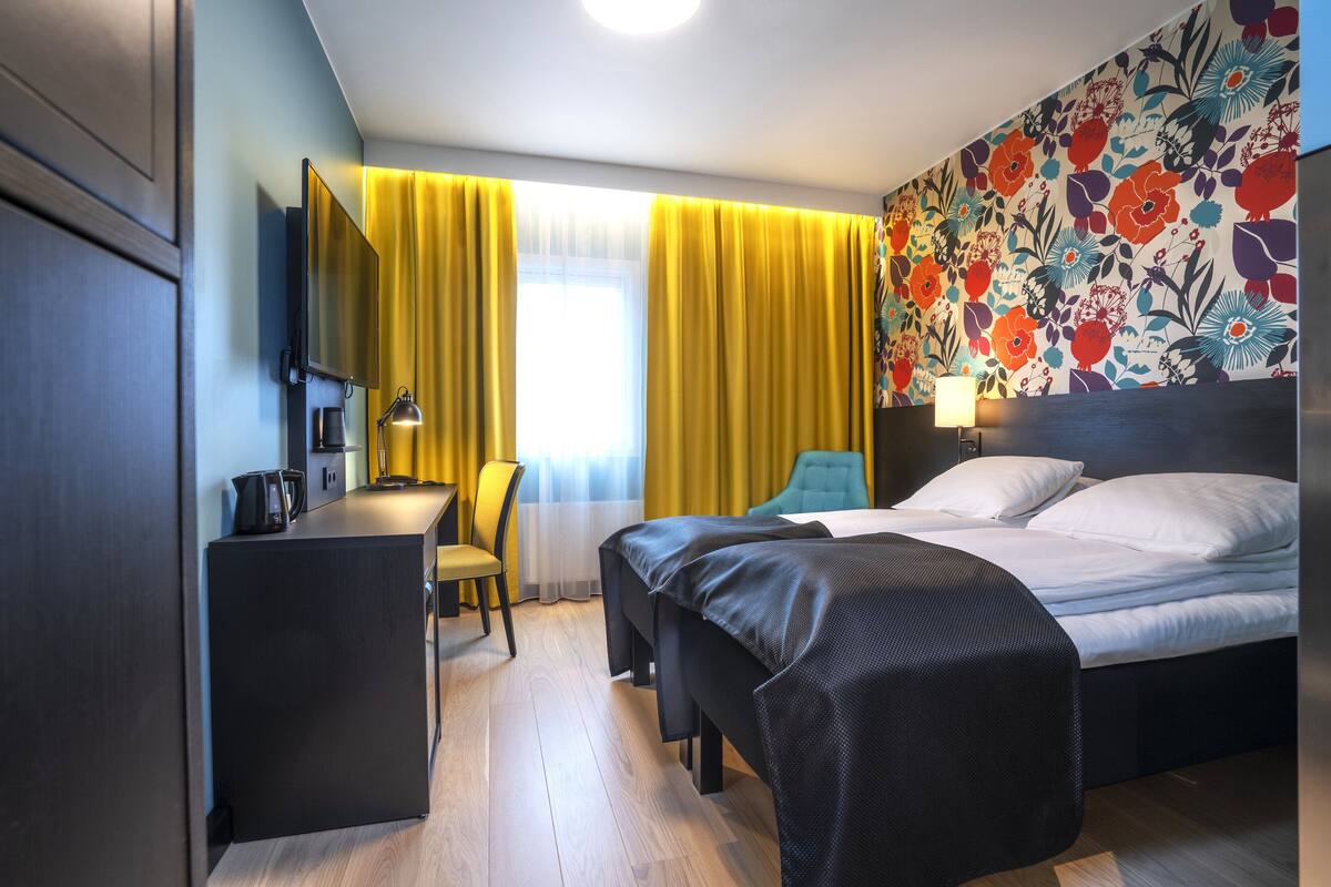 A hotel room with a bed, a desk, a chair, and a TV.