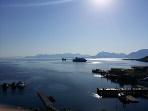 A calm harbor with boats docked, a pier, and distant mountains under a clear sky. - Thon Hotel Harstad (Harstad)