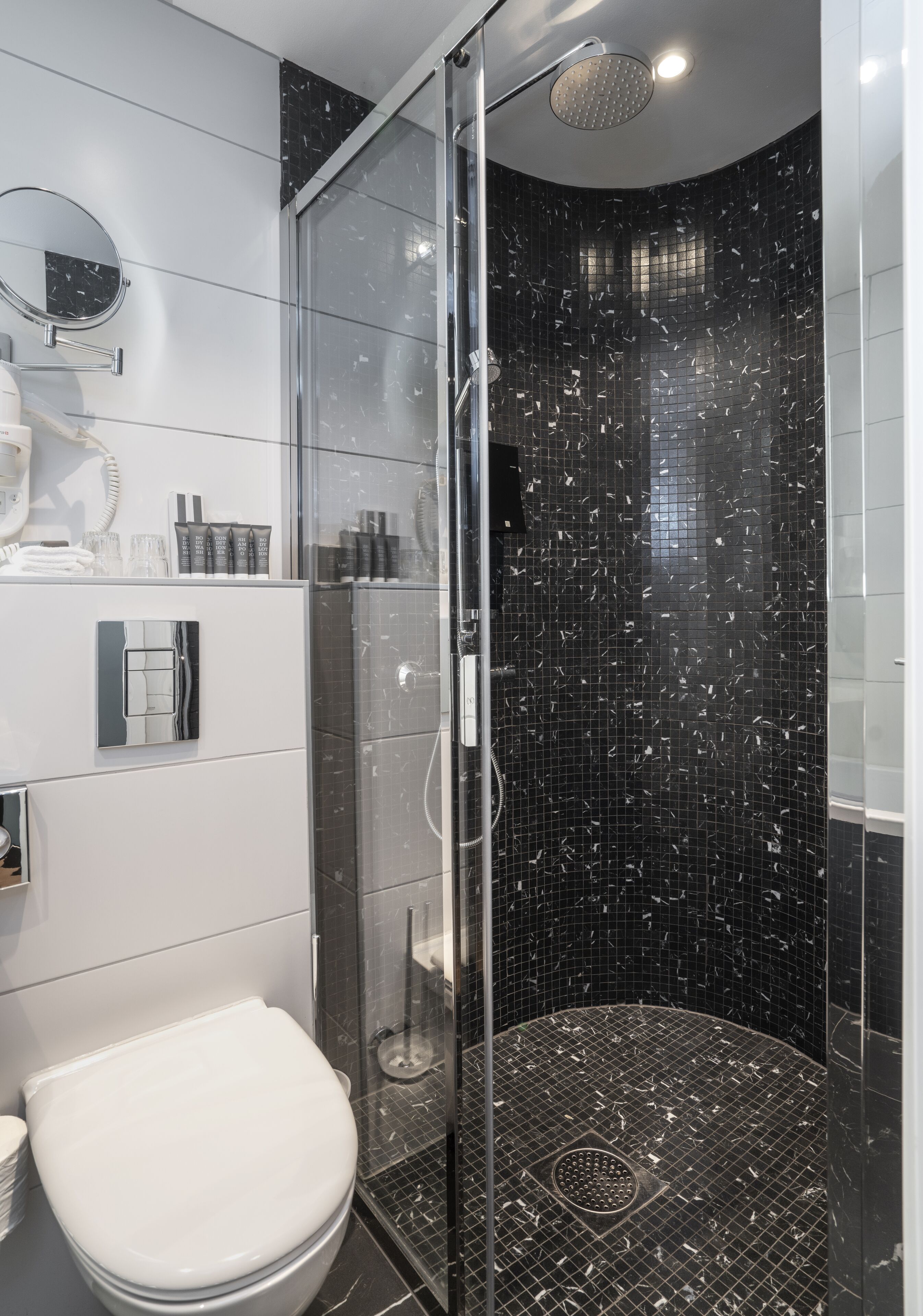 Ein modernes Badezimmer mit einer Duschkabine, einer Toilette und einem Waschbeckenbereich mit Pflegeartikeln.