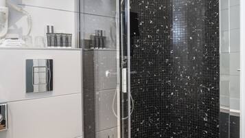 Ein modernes Badezimmer mit einer Duschkabine, einer Toilette und einem Waschbeckenbereich mit Pflegeartikeln.