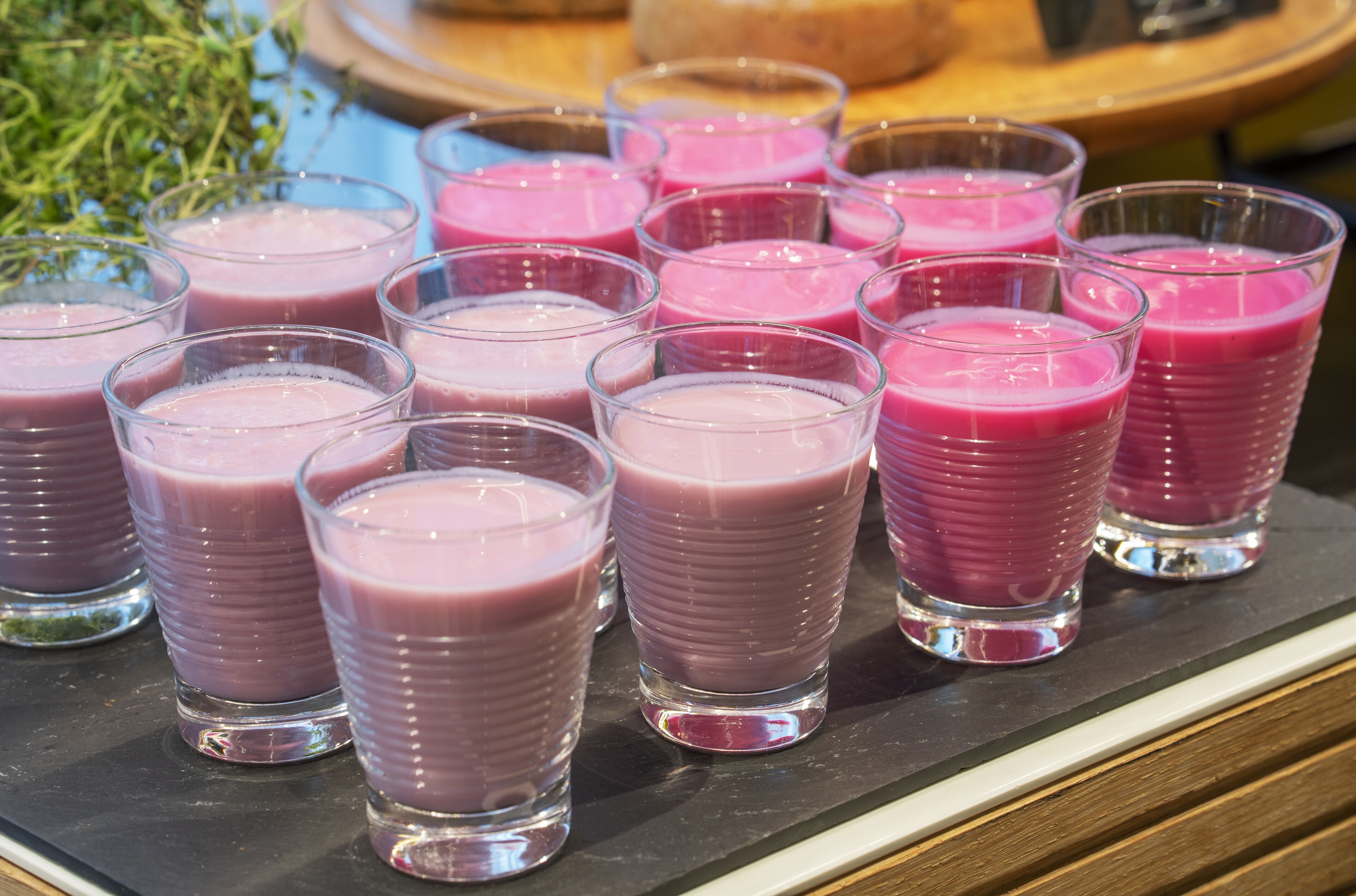 Un plateau rempli de verres contenant des smoothies roses.