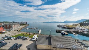 A marina with boats docked, a parking lot, and buildings with a view of the water. - Thon Hotel Harstad (Harstad)