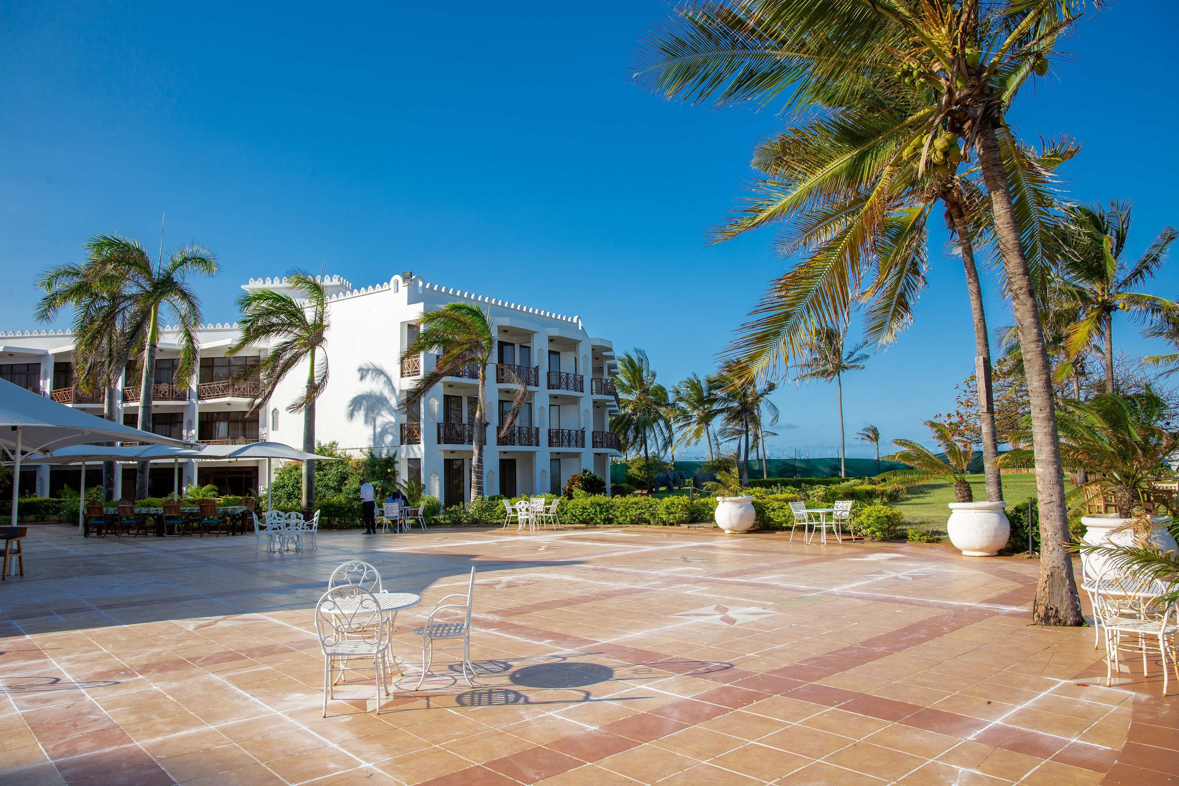 A resort with a pool area, outdoor seating, and palm trees.