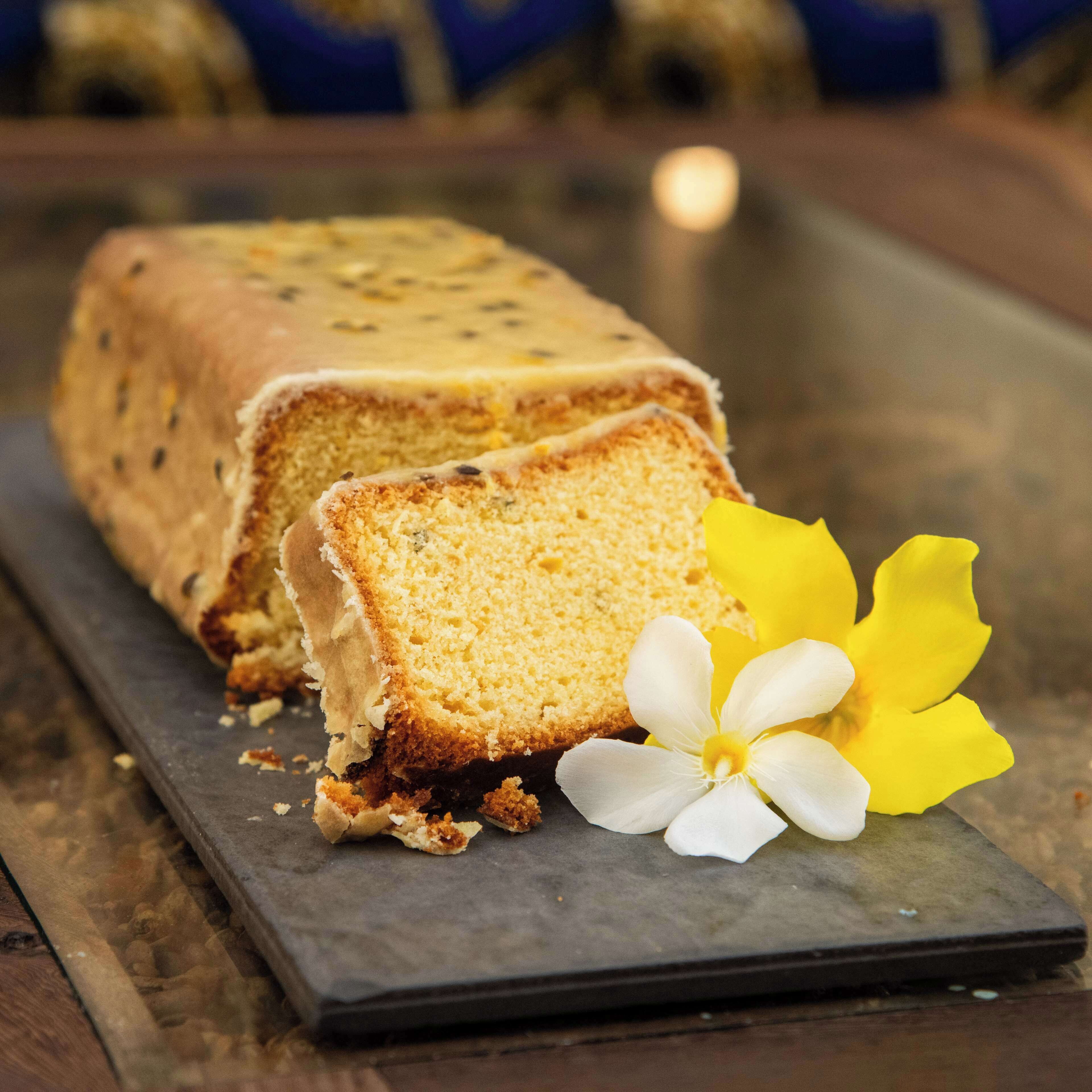 Une miche de pain, ornée d’une fleur, posée sur un plateau de service en ardoise.