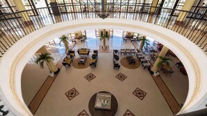 Eine großzügige Lobby mit einer zentralen Sitzgelegenheit, mehreren Tischen und einer großen Chandelier.