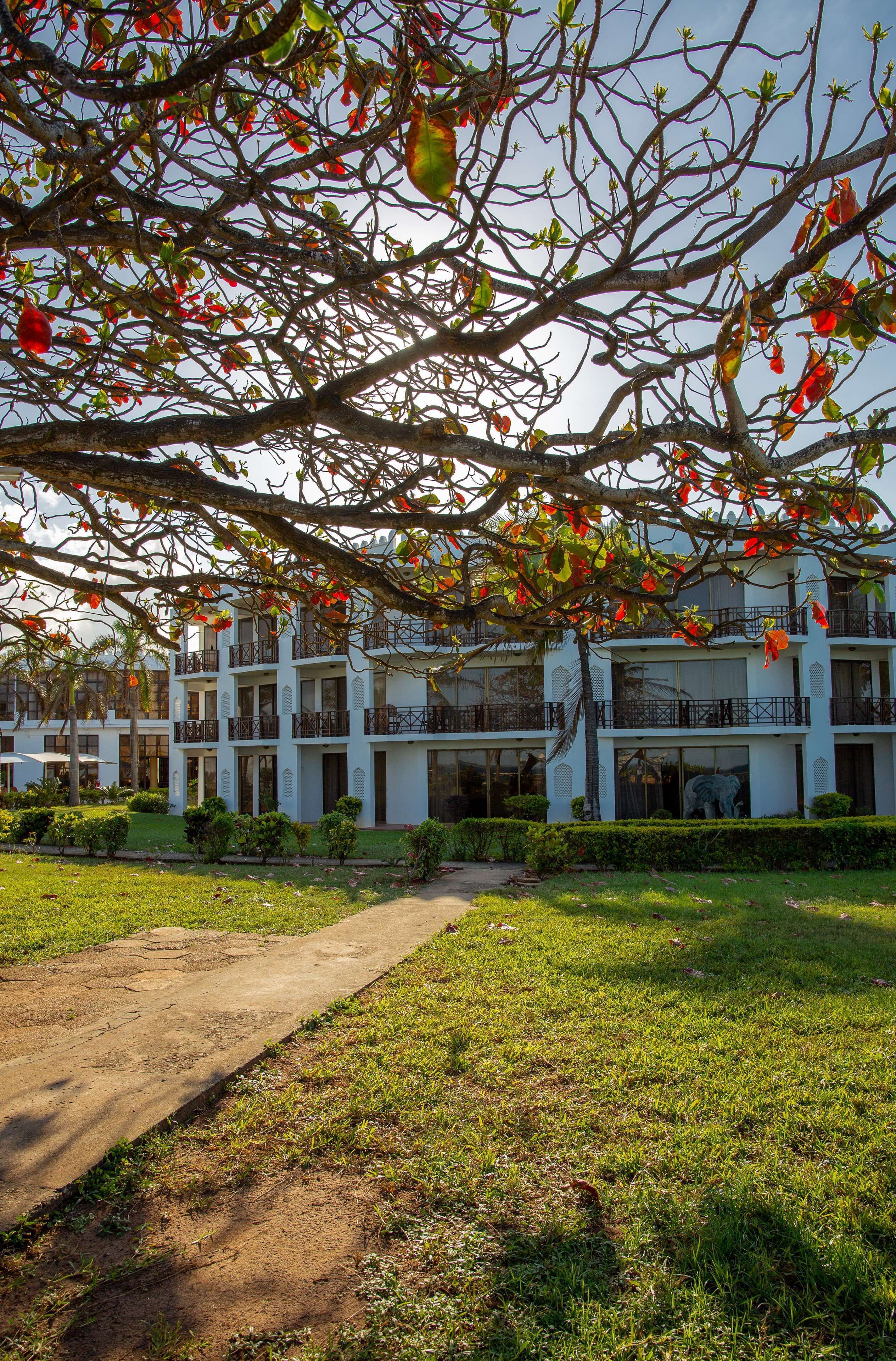 A hotel with a multi-story structure, a paved pathway, and a well-maintained lawn.